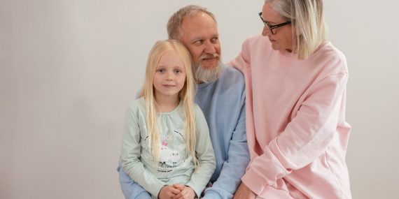 Grandparents lovingly embrace their granddaughter in a bright, studio setting, capturing family warmth and connection.