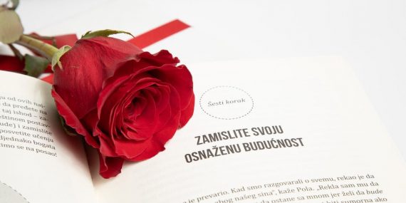 Close-up of a vibrant red rose placed on an open book, symbolizing romance and beauty.