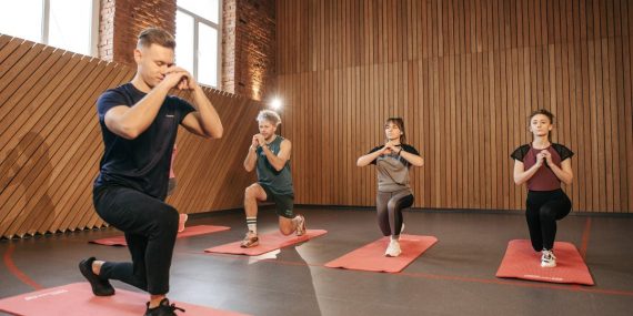 Adults practicing exercises on yoga mats in a contemporary studio setting.